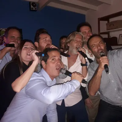Grupo de invitados cantando juntos con micrófonos en un show de karaoke